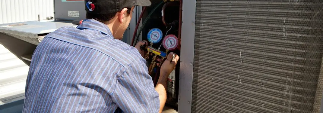 HVAC technician servicing a condenser unit in Peoria